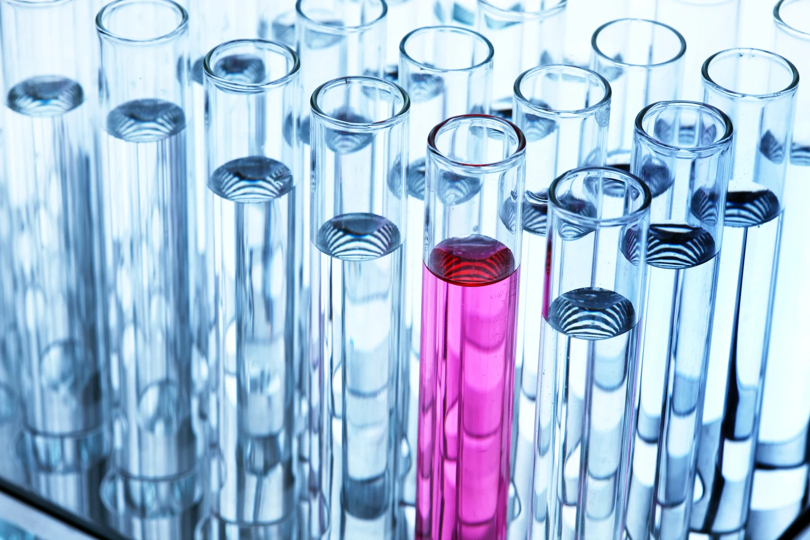 Eine Wissenschaftlerin und ein Wissenschaftler arbeiten hinter einer Glasfassade und mischen Chemikalien mit Großgeräten.