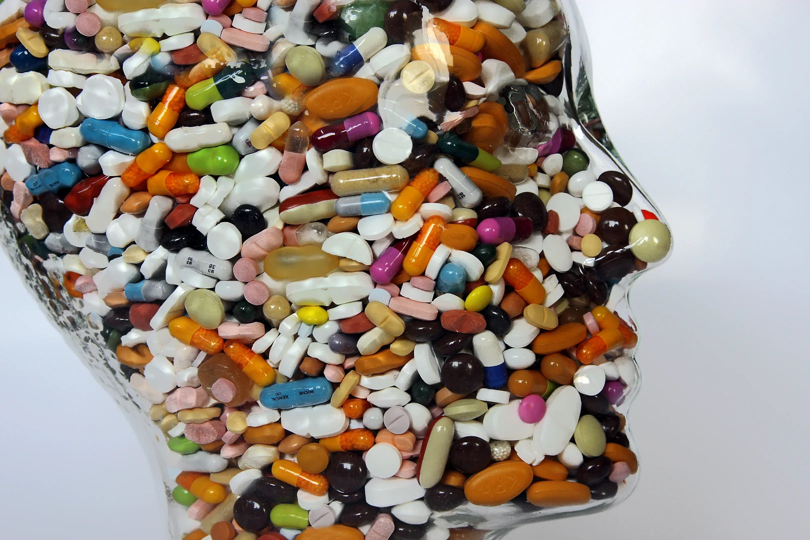 Eine Wissenschaftlerin und ein Wissenschaftler arbeiten hinter einer Glasfassade und mischen Chemikalien mit Großgeräten.